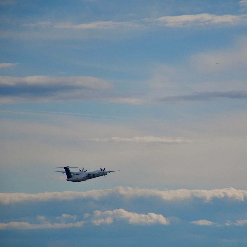 A small aircraft flying through a blue sky with soft clouds, showcasing a sense of tranquility and open space.